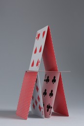 Photo of House of playing cards on light grey background