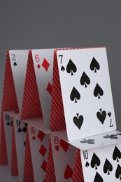 Photo of House of playing cards on grey background, closeup