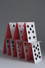 Photo of House of playing cards on grey background