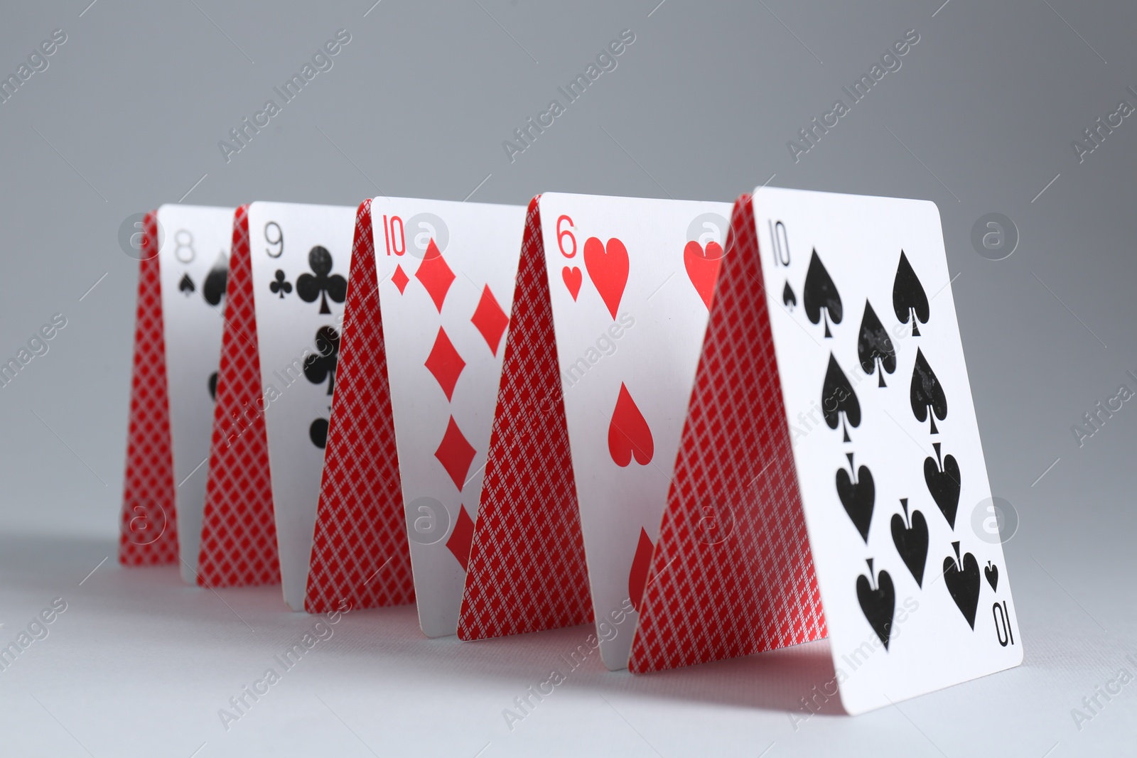 Photo of Row of playing cards on grey background, closeup