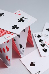 Photo of Collapsed house of playing cards on light grey background, closeup