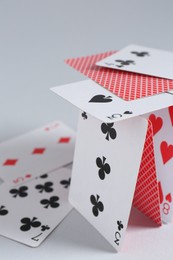 Photo of Collapsed house of playing cards on light grey background, closeup