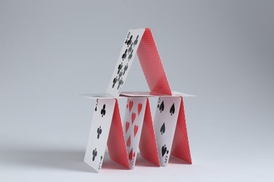 Photo of House of playing cards on light grey background