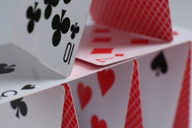 Photo of House of playing cards on light grey background, closeup