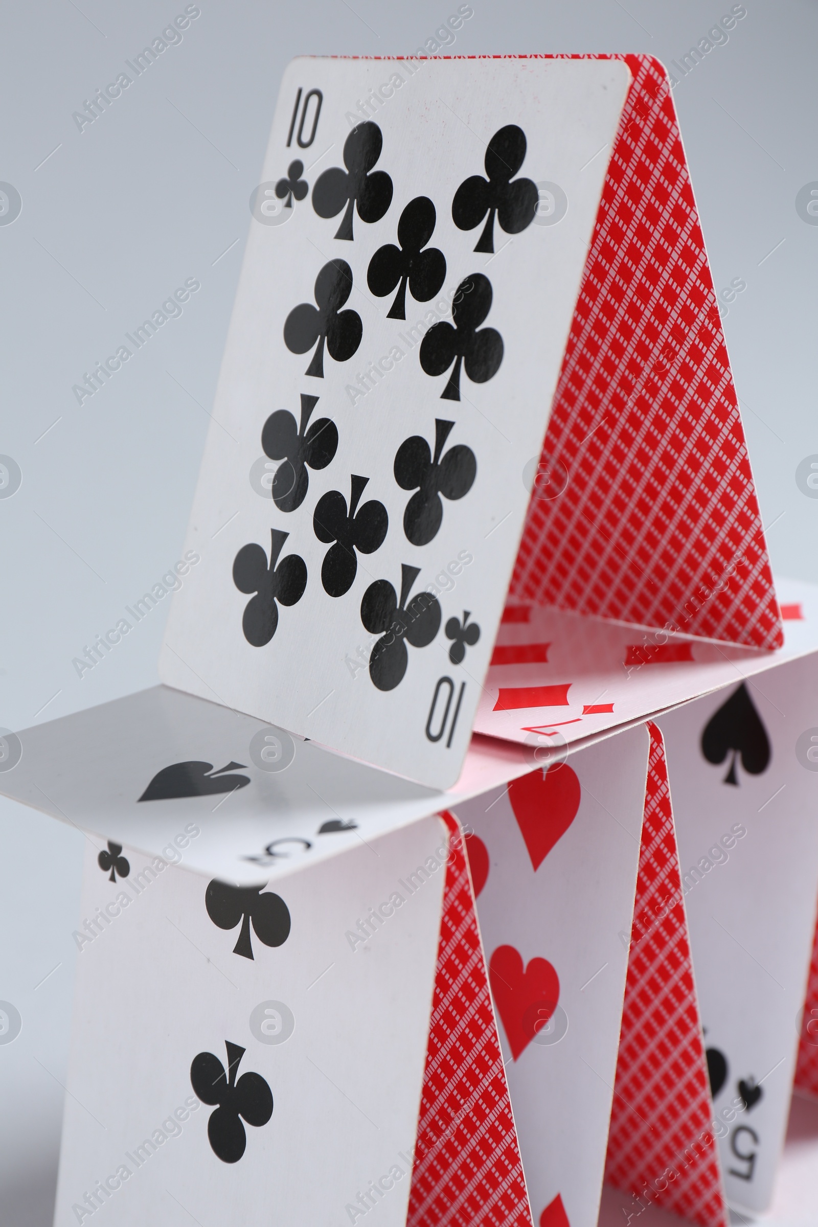 Photo of House of playing cards on light grey background, closeup