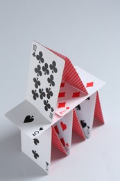 Photo of House of playing cards on light grey background