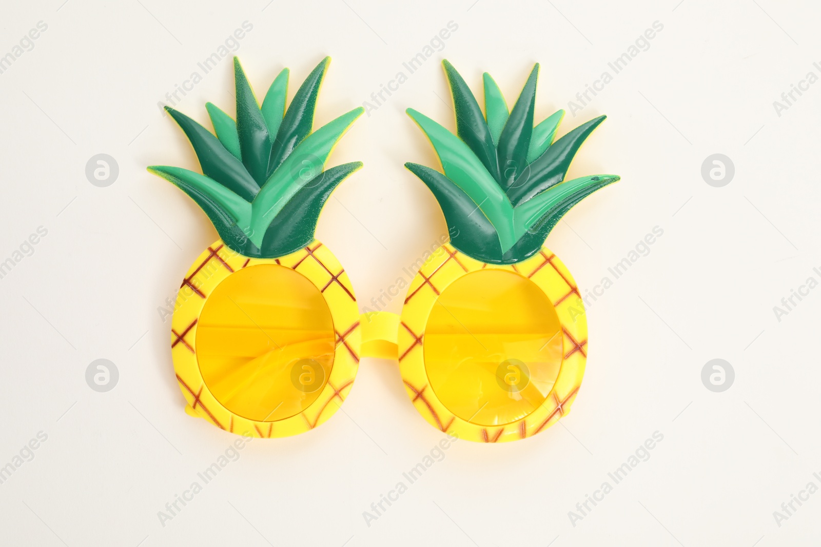 Photo of Creative pineapple shaped sunglasses on white background, top view