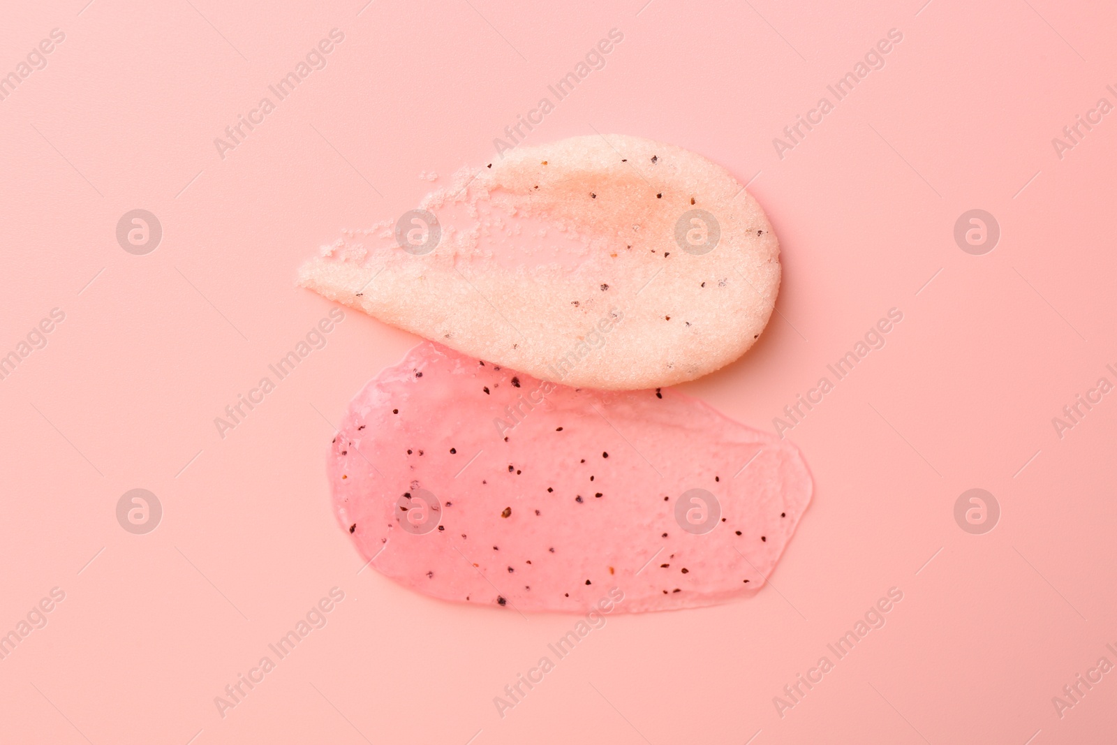 Photo of Smears of body scrubs on light pink background, top view