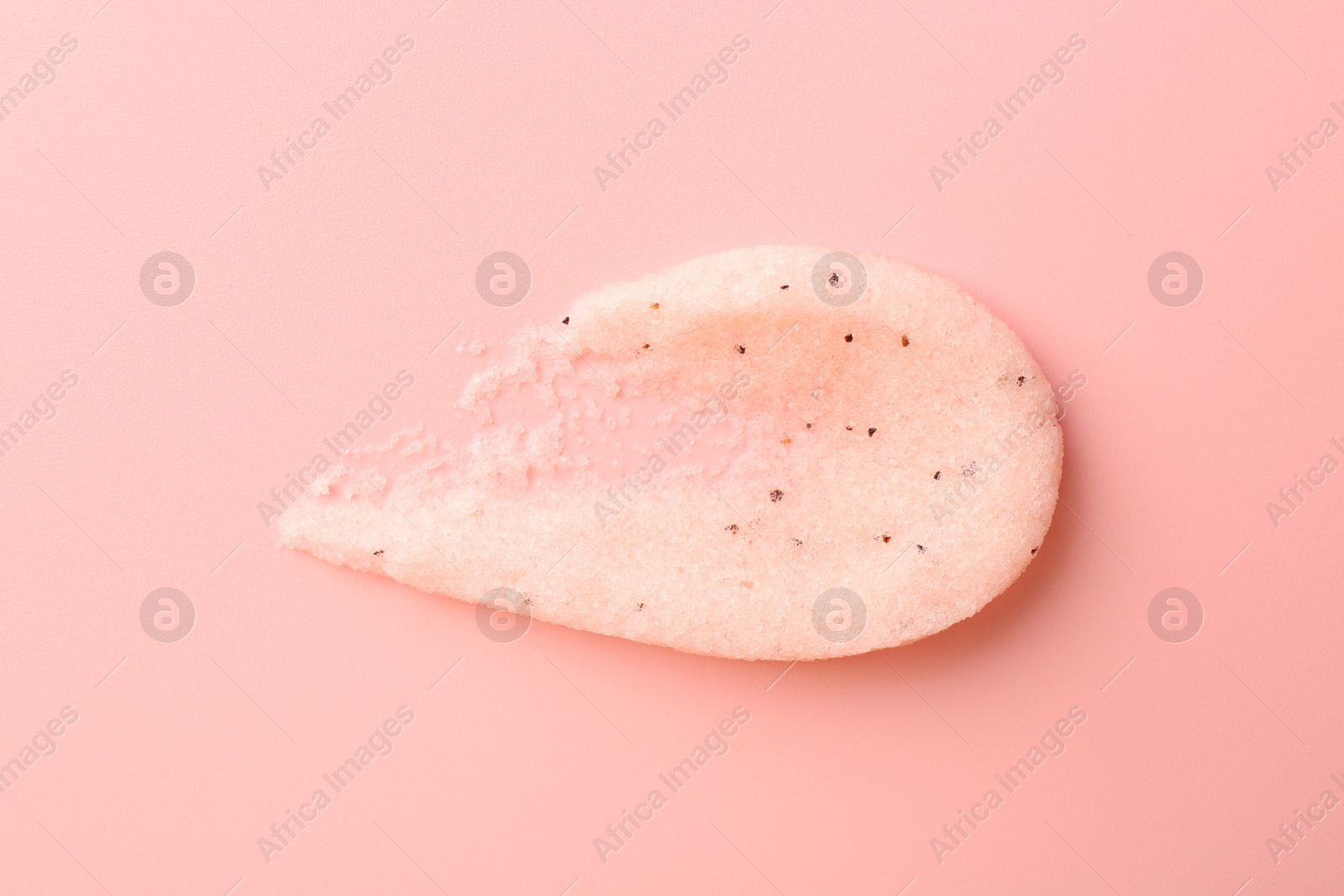 Photo of Smear of body scrub on light pink background, top view