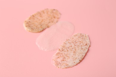 Photo of Smears of body scrubs on light pink background, closeup