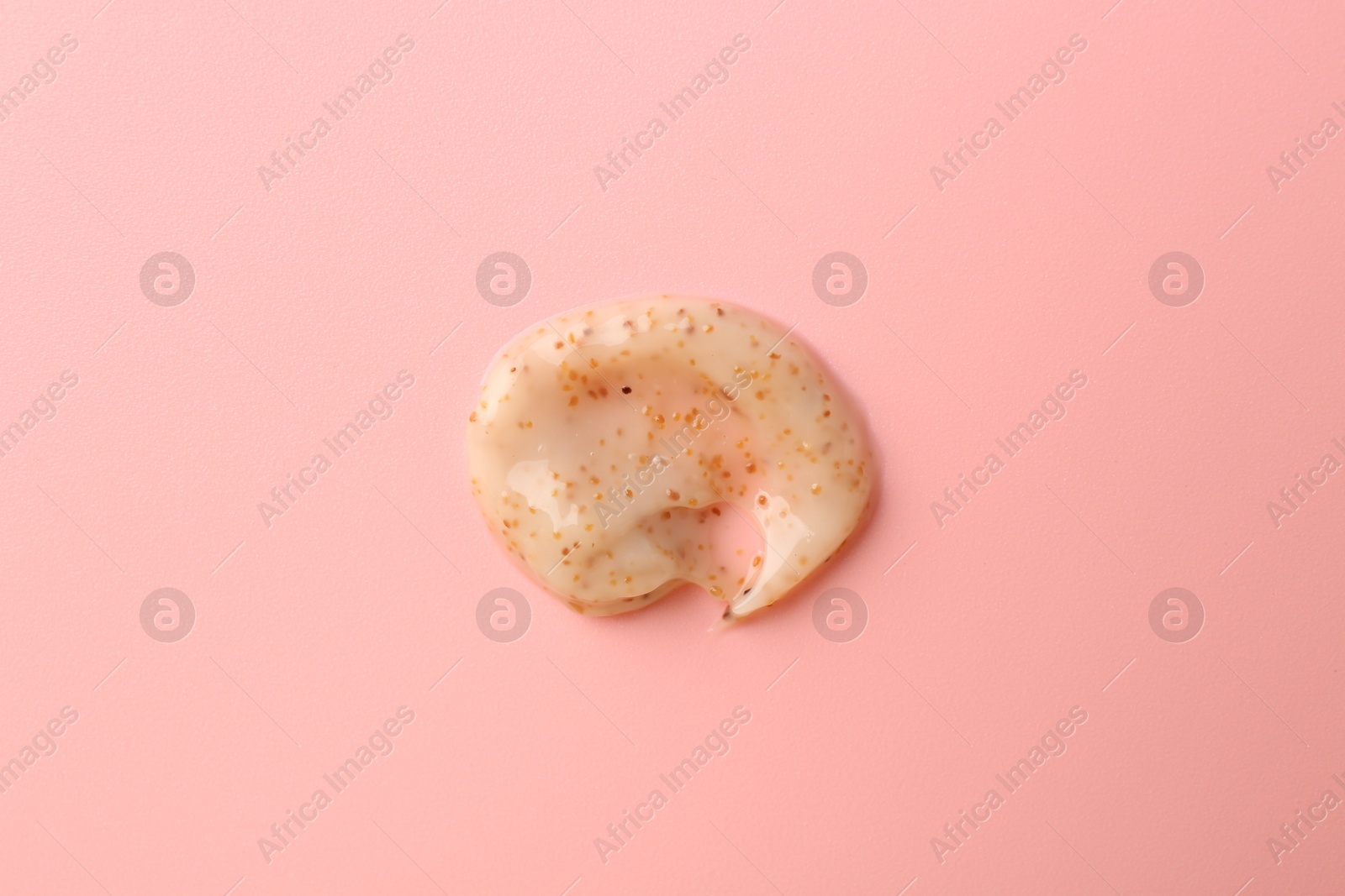 Photo of Smear of body scrub on light pink background, top view