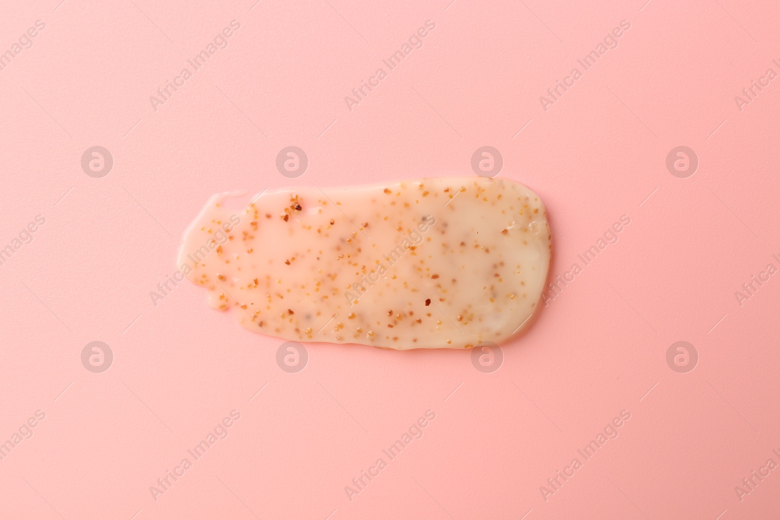 Photo of Smear of body scrub on light pink background, top view