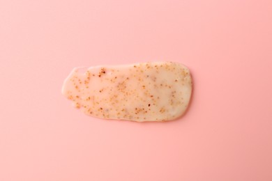 Photo of Smear of body scrub on light pink background, top view