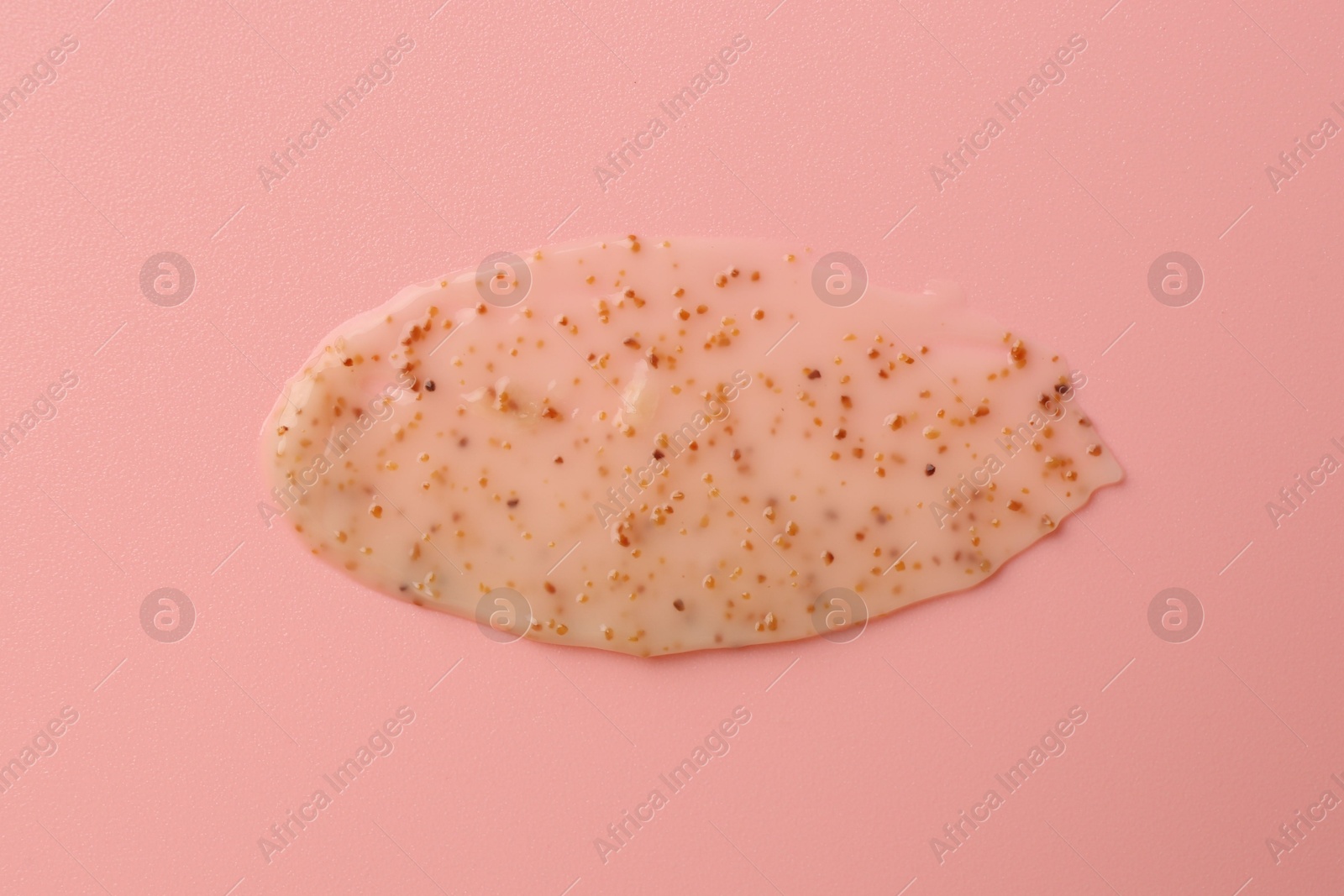 Photo of Smear of body scrub on light pink background, top view