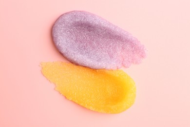 Smears of body scrubs on light pink background, top view