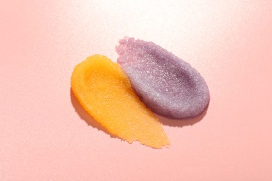 Photo of Smears of body scrubs on light pink background, closeup