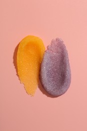 Photo of Smears of body scrubs on light pink background, top view