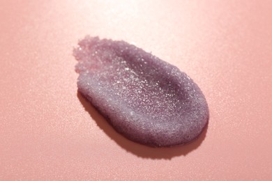 Photo of Smear of body scrub on light pink background, closeup