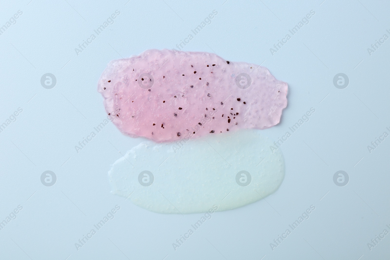 Photo of Smears of body scrubs on light pink background, top view