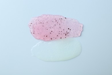 Photo of Smears of body scrubs on light pink background, top view