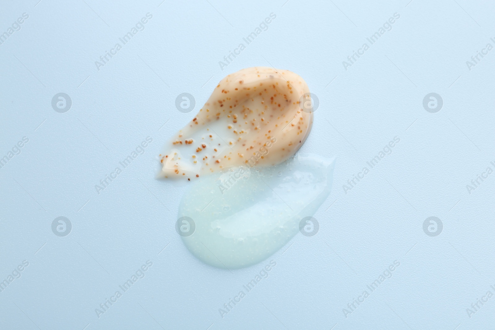 Photo of Smears of body scrubs on light blue background, top view