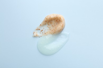 Photo of Smears of body scrubs on light blue background, top view