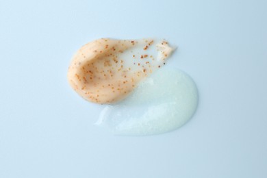 Photo of Smears of body scrubs on light blue background, top view