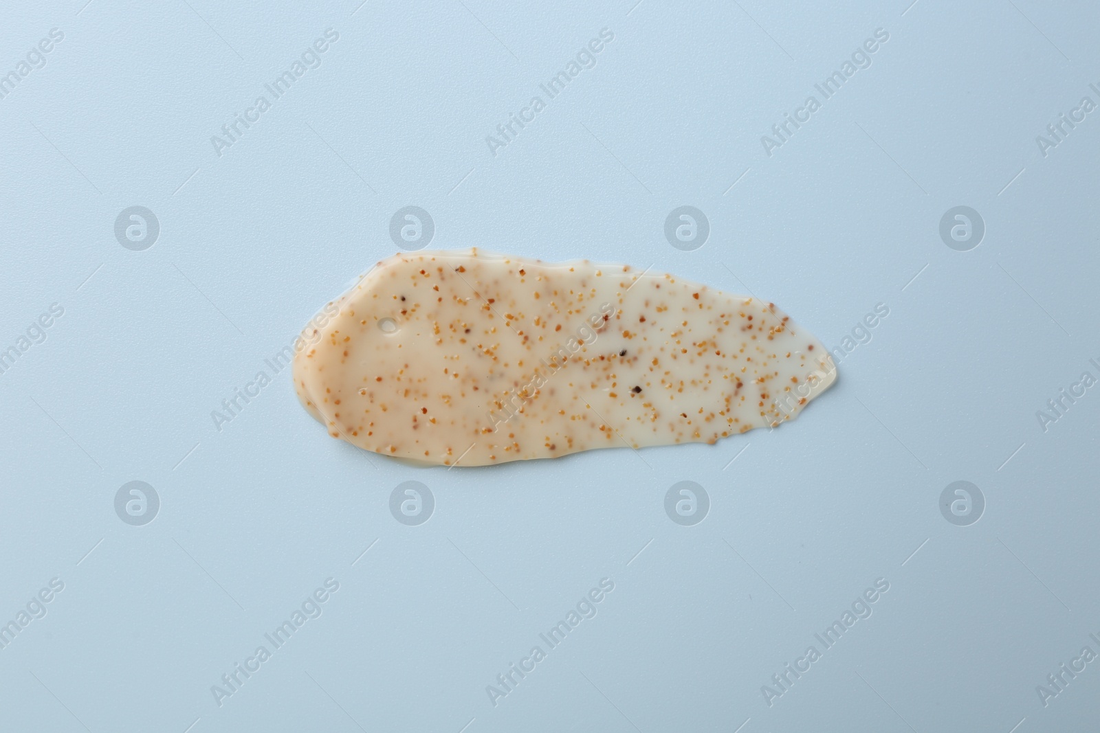 Photo of Smear of body scrub on light blue background, top view