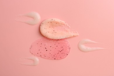 Photo of Smears of body scrubs on light pink background, flat lay