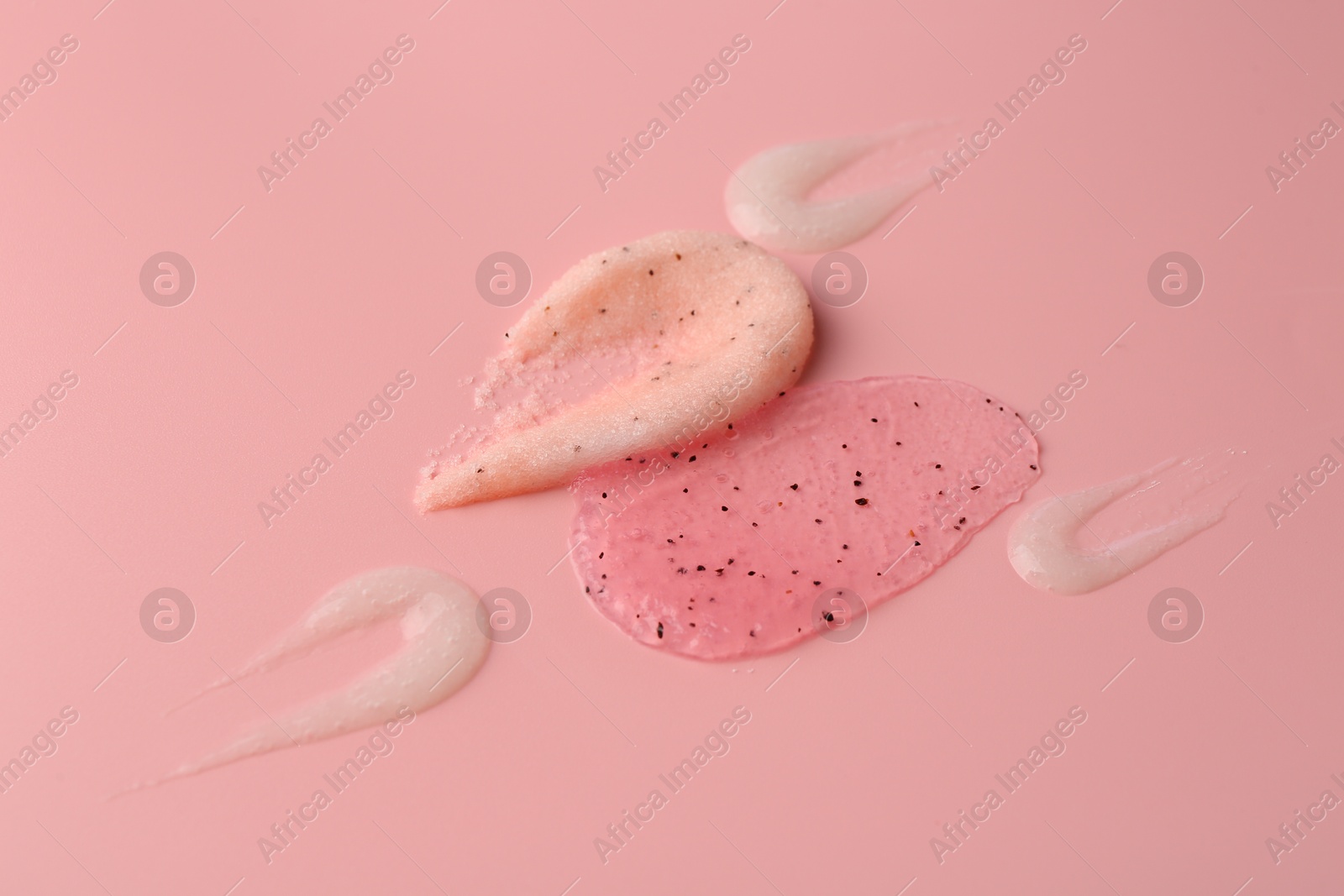 Photo of Smears of body scrubs on light pink background, closeup