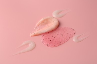 Photo of Smears of body scrubs on light pink background, closeup