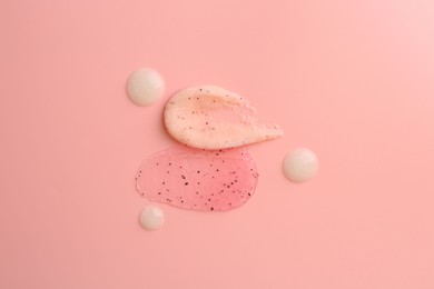 Photo of Smears of body scrubs on light pink background, flat lay