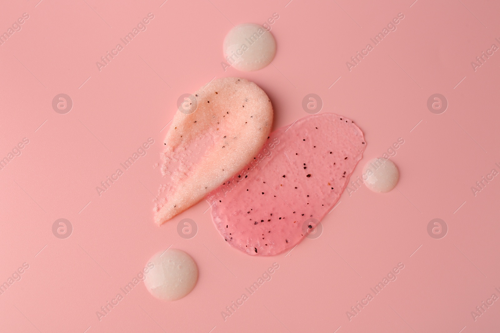 Photo of Smears of body scrubs on light pink background, flat lay