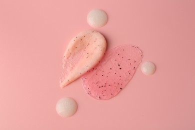 Photo of Smears of body scrubs on light pink background, flat lay