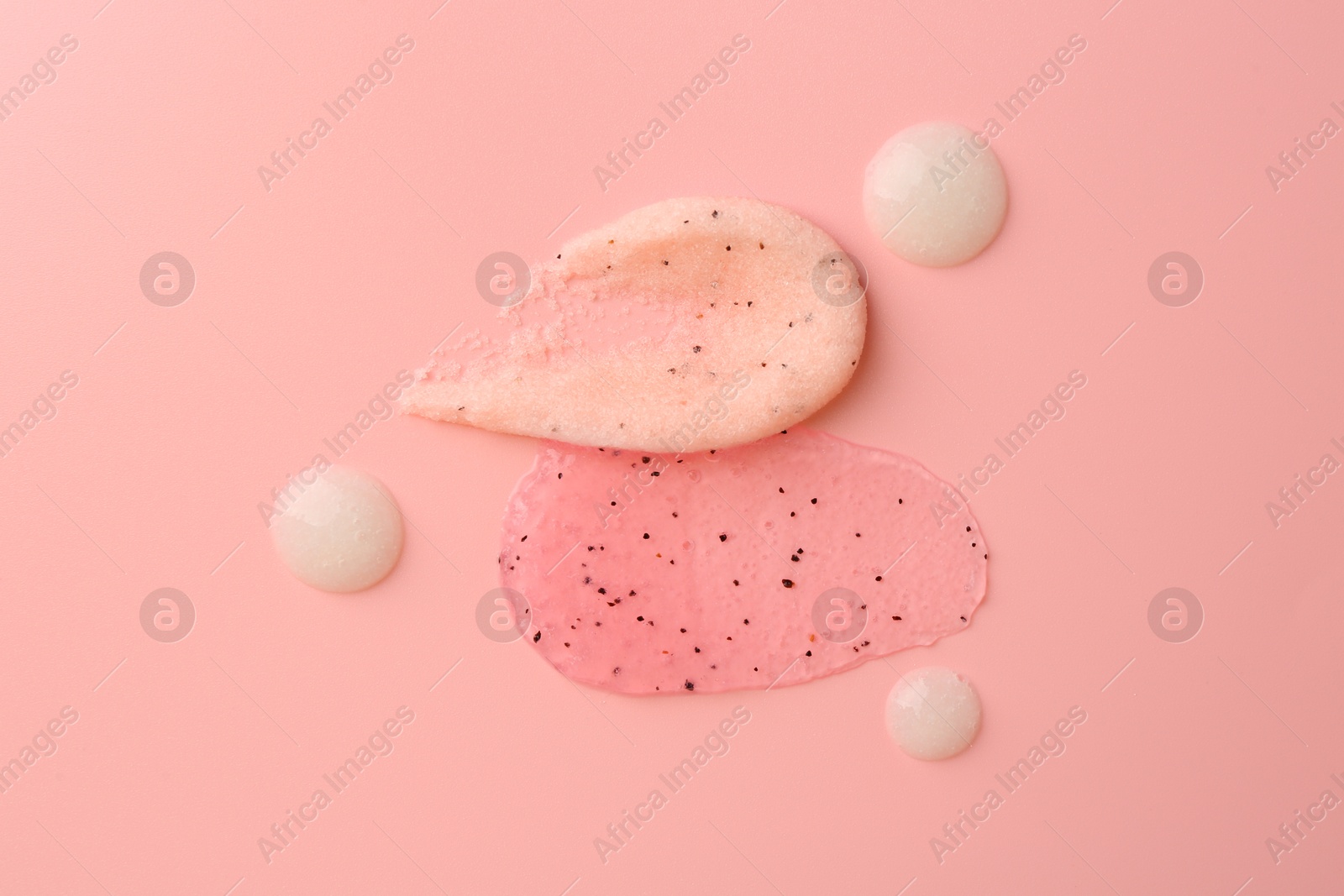 Photo of Smears of body scrubs on light pink background, flat lay