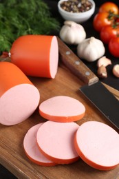 Photo of Tasty boiled sausage, knife, spices and tomatoes on table, closeup