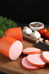 Photo of Tasty boiled sausage, knife, spices and tomatoes on table, closeup