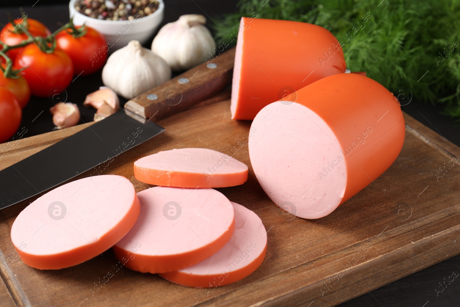 Photo of Tasty boiled sausage, knife, spices and tomatoes on table, closeup