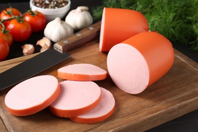 Photo of Tasty boiled sausage, knife, spices and tomatoes on table, closeup