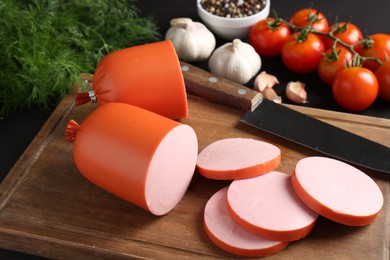 Photo of Tasty boiled sausage, knife, spices and tomatoes on table, closeup