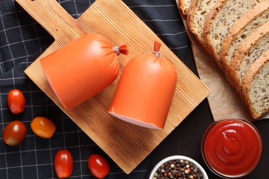 Photo of Tasty boiled sausage, ketchup, tomatoes, spices and bread on table, top view