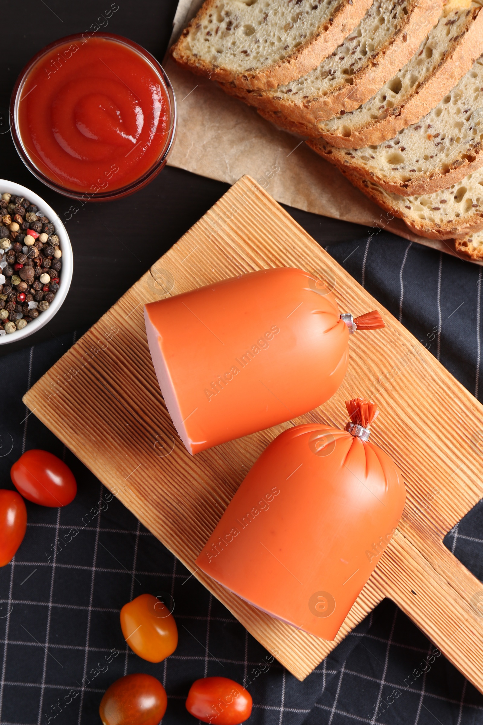 Photo of Tasty boiled sausage, ketchup, tomatoes, spices and bread on table, top view