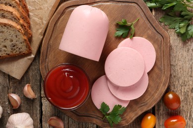 Photo of Tasty boiled sausage, ketchup, tomatoes, spices and bread on wooden table, top view