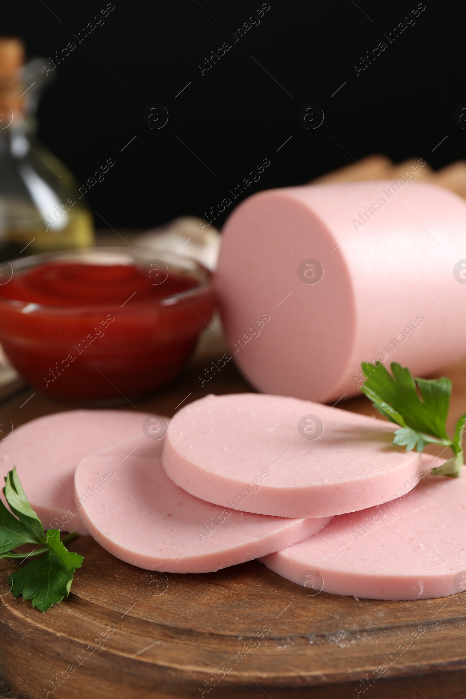 Photo of Tasty boiled sausage, ketchup and parsley on table, closeup