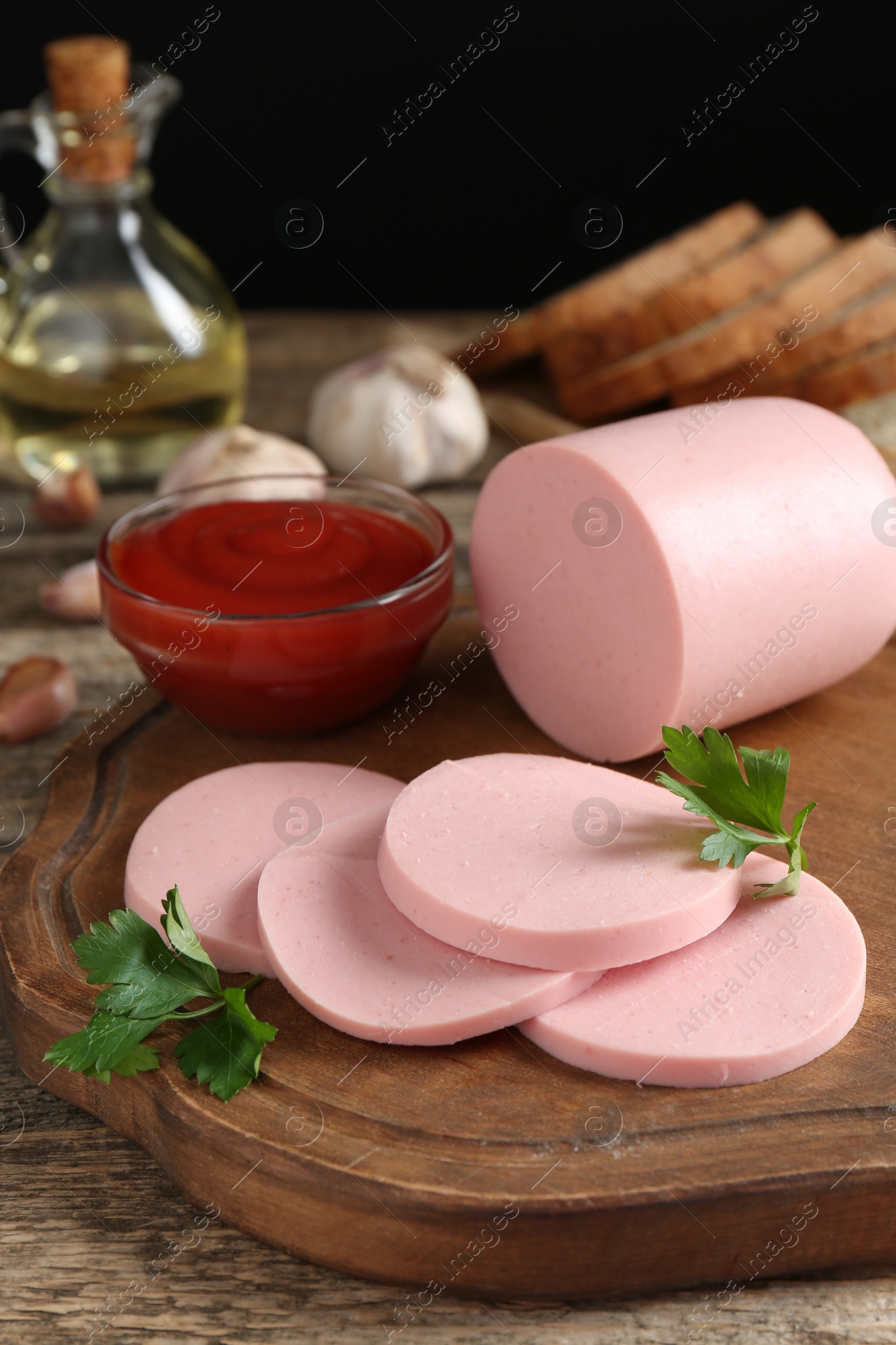 Photo of Tasty boiled sausage, ketchup and parsley on wooden table, closeup