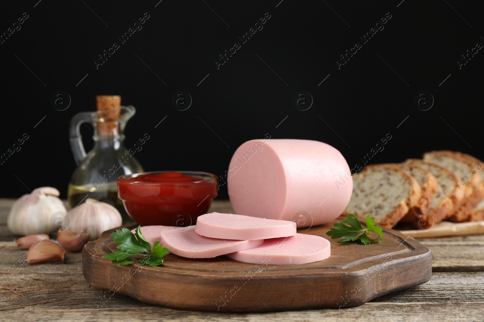 Photo of Tasty boiled sausage, ketchup, spices and bread on wooden table