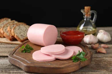 Photo of Tasty boiled sausage, ketchup, spices and bread on wooden table, closeup