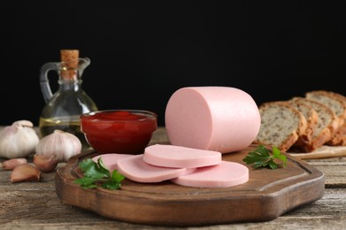 Photo of Tasty boiled sausage, ketchup, spices and bread on wooden table, closeup