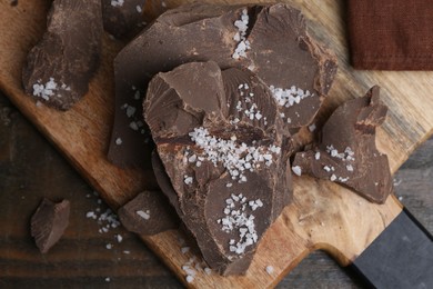 Photo of Pieces of chocolate with salt on wooden table, above view