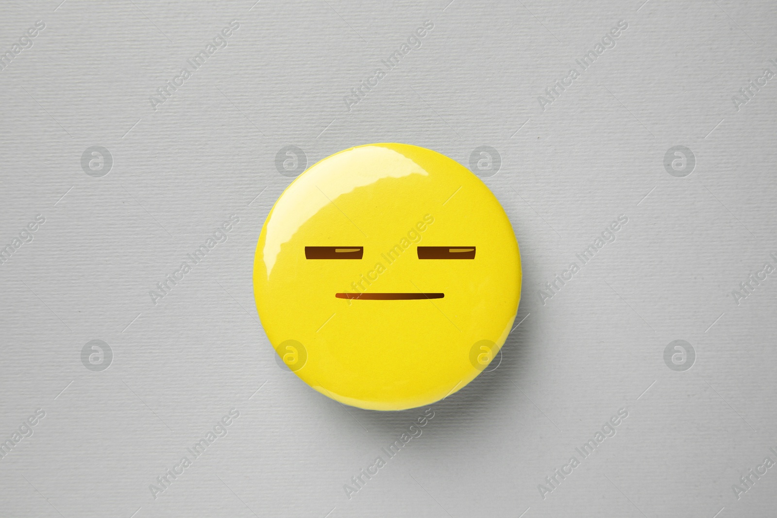 Image of Badge with distrustful or sleepy face on grey background